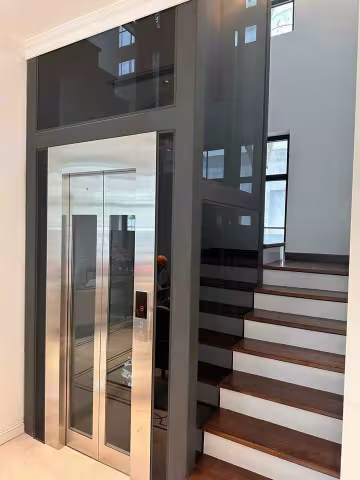 Thang máy lồng kính đặt giữa cầu thang gỗ