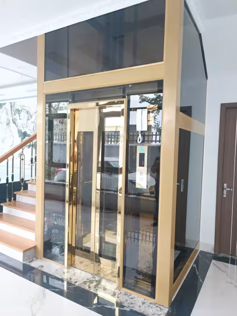 Thang máy kính khung vàng đồng lắp trong biệt thự, cabin cửa inox vàng gương